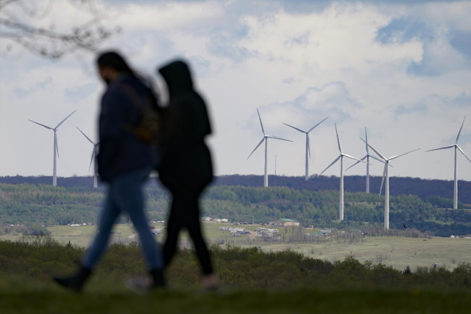 People are silhouetted as they stroll past power generating wind turbines visible from a walking path at the Flight 93 National Memorial in Shanksville, Pa., Saturday, May 8, 2021. (AP Photo/Keith Srakocic)