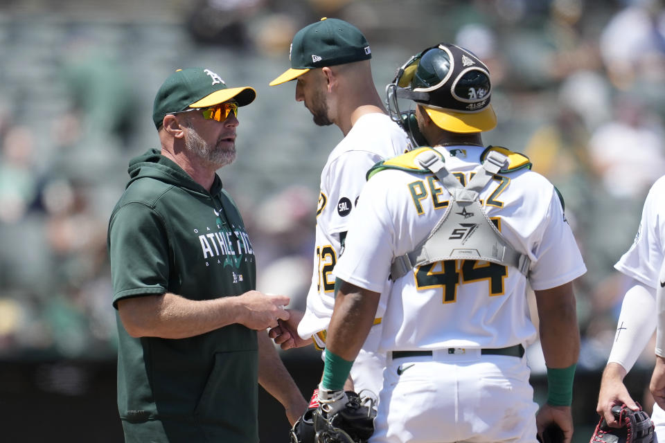 Oakland Athletics manager Mark Kotsay, left, takes the ball from pitcher James Kaprielian, center, while making a pitching change during the sixth inning of a baseball game against the Philadelphia Phillies in Oakland, Calif., Saturday, June 17, 2023. Athletics catcher Carlos Perez (44) looks on. (AP Photo/Jeff Chiu)