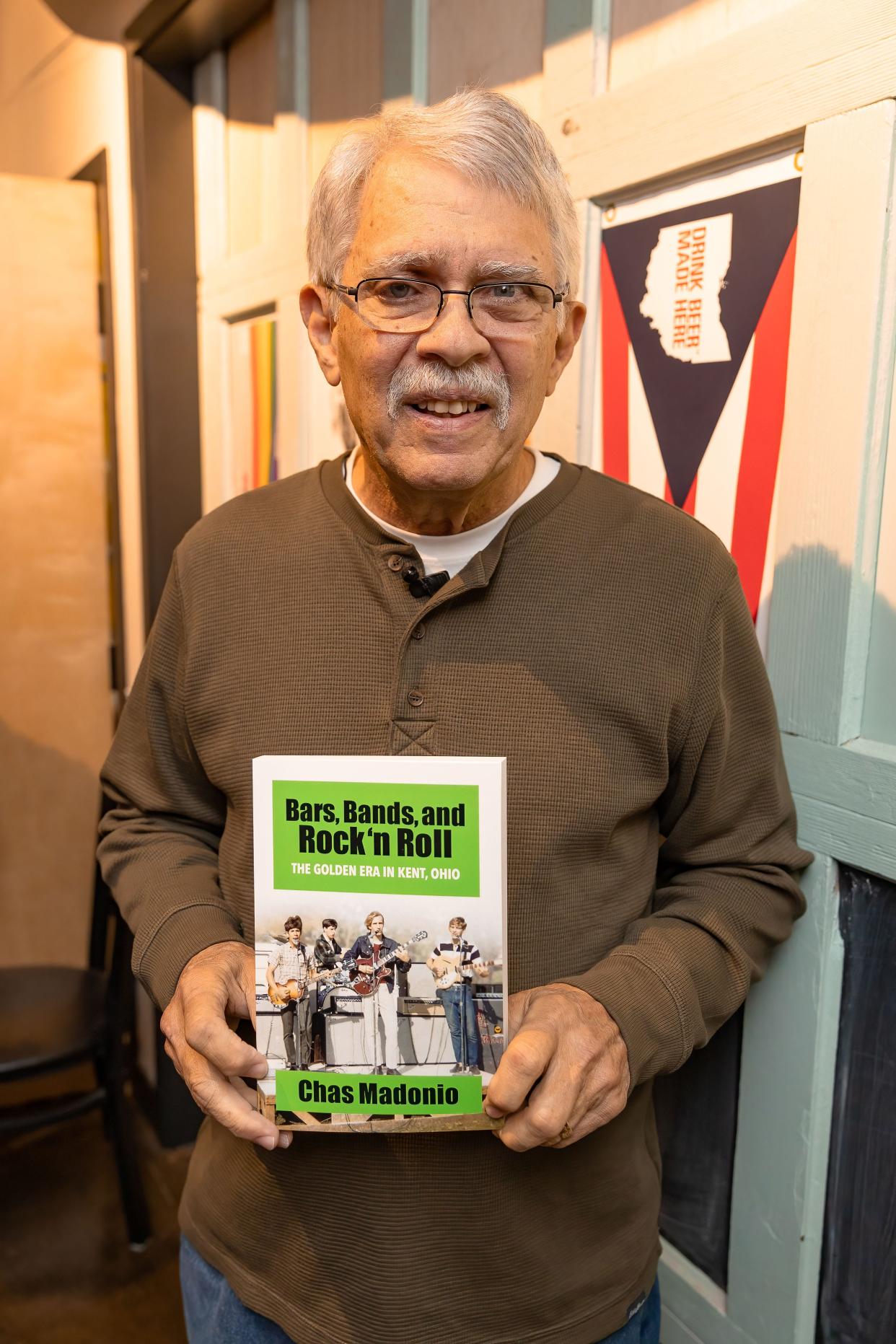 Author Chas Madonio holds a copy of his book, “Bars, Bands, and Rock 'n Roll - The Golden Era in Kent, Ohio”, at a book release event Tuesday at the North Water Brewing Co. in Kent.