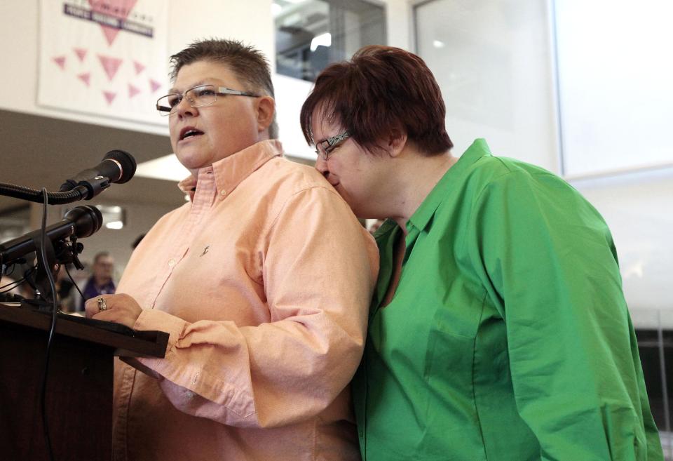 Jayne Rowse, left, speaks as April DeBoer, kisses her during a news conference in Ferndale, Mich., Friday, March 21, 2014. A federal judge has struck down Michigan's ban on gay marriage Friday the latest in a series of decisions overturning similar laws across the U.S. The two nurses who've been partners for eight years claimed the ban violated their rights under the U.S. Constitution. (AP Photo/Paul Sancya)