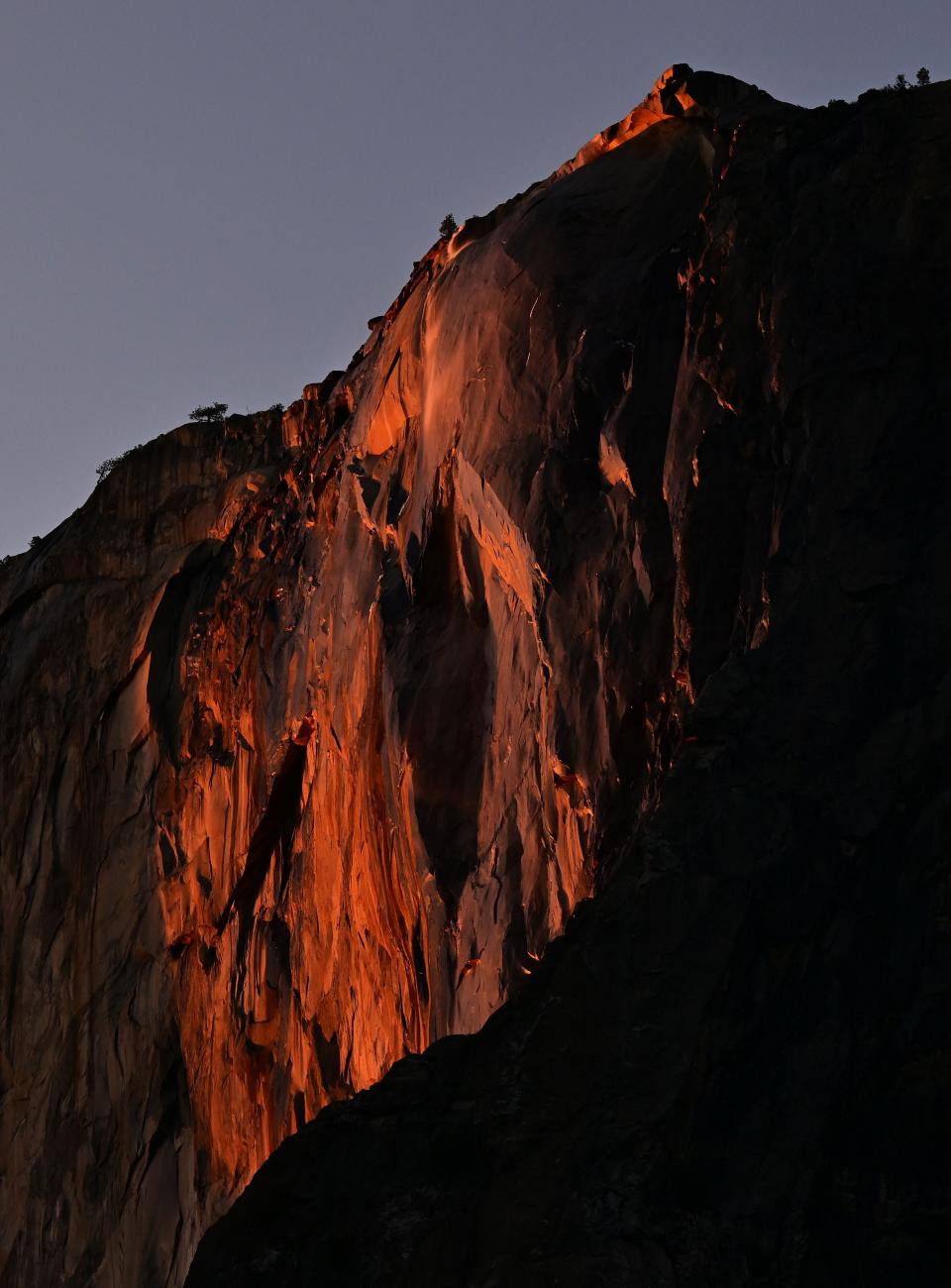 Water flowing off Horsetail Fall glows orange while backlit from the setting sun during the "Firefall" phenomenon in Yosemite National Park, California on February 15, 2023.