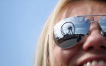 The giant ferris wheel is reflected in the glasses of a young woman at the Oktoberfest.