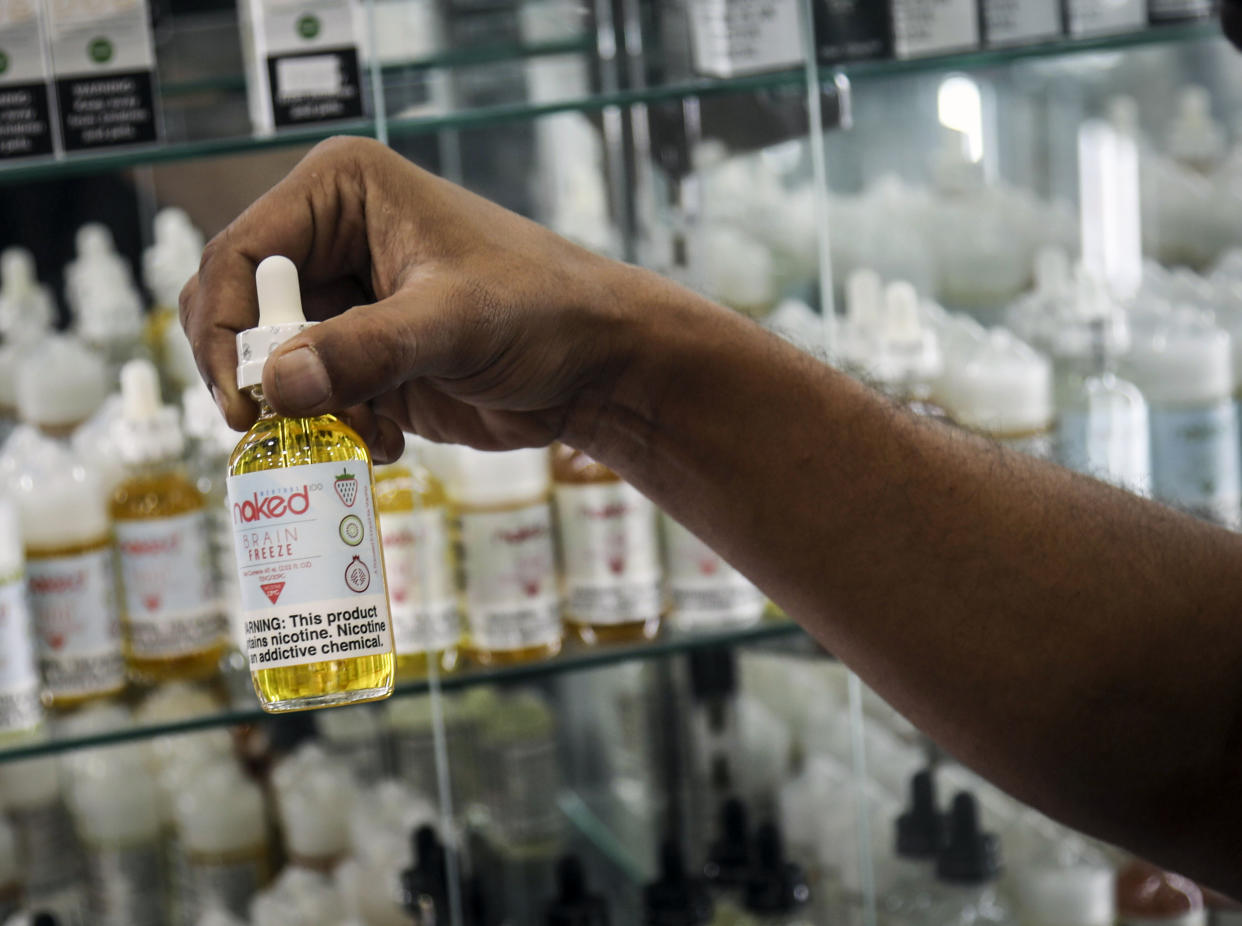 Inam Rehman, manager of Jubilee Vape & Smoke Inc., displays a flavored vaping solution his store sells, Monday Sept. 16, 2019, in New York. New York Gov. Andrew Cuomo is pushing to enact a statewide ban on the sale of flavored e-cigarettes amid growing health concerns of vaping. (AP Photo/Bebeto Matthews)