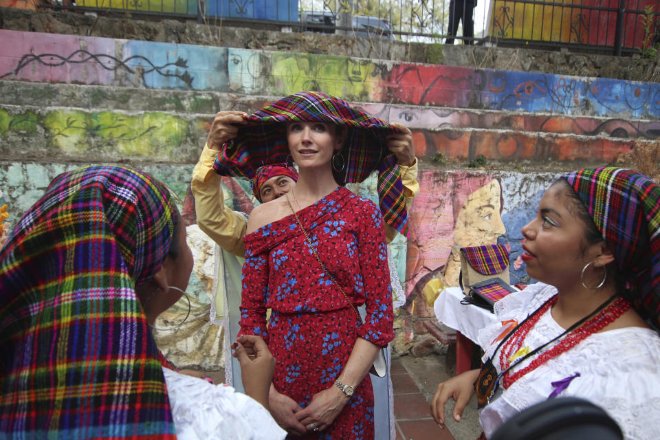 Jennifer Siebel Newsom, wife of California Gov. Gavin Newsom, receives help from dance students, to place on her head a traditional Panchimalco shawl worn by women in the last century, during a visit to Panchimalco, the home of indigenous Salvadorans, El Salvador, Monday, April 8, 2019. The governor and his wife later watched performances at a cultural center that aims to teach children traditional crafting, song and dance to help them build job skills in Panchimalco, a rural community surrounded by largely gang-controlled areas. (AP Photo/Salvador Melendez)
