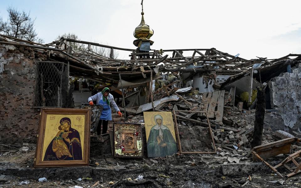 A woman collects Orthodox icons at a site of a church destroyed by a Russian missile strike - STRINGER/REUTERS