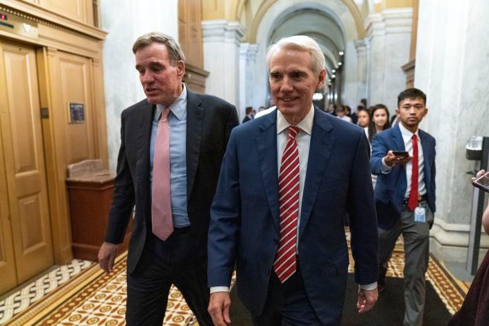 Sen. Mark Warner, D-Va., left, accompanied by Sen. Rob Portman, R-Ohio, walk for closed door talks about infrastructure on Capitol Hill in Washington July 15.