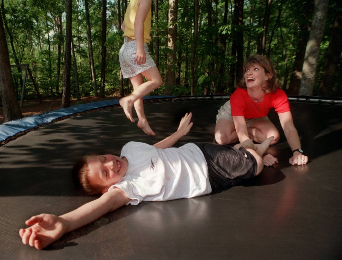 Donna Gregory, former newscaster for WRAL, plays with her daughter, Callan, 5, and her son, Sam, 7, on the trampoline in their backyard in Cary, in 1997. Corey Lowenstein/The News & Observer