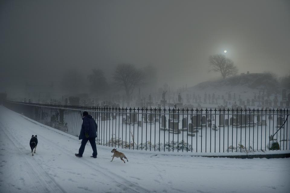 STIRLING, UNITED KINGDOM - DECEMBER 03: A man walks his two dogs past Stirling Castle graveyard on December 3, 2012 in Stirling, Scotland. Snow and sleet has hit many parts of Scotland with heavier falls expected over higher grounds. (Photo by Jeff J Mitchell/Getty Images)