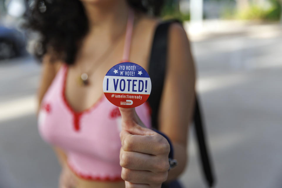 Nicole Montesinos, in halter top, poses with a sticker that also says in Spanish: Yo Voté! M' Vote!