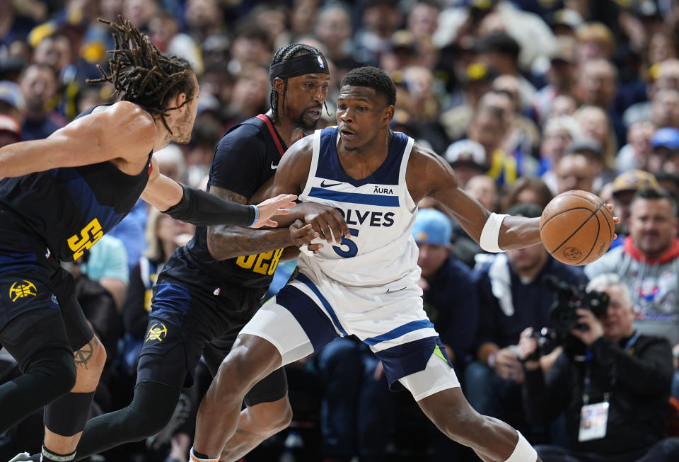 Minnesota Timberwolves guard Anthony Edwards, center, looks to pass the ball as Denver Nuggets forward Aaron Gordon, left, and guard Kentavious Caldwell-Pope, center, defend in the first half of Game 2 of an NBA basketball second-round playoff series Monday, May 6, 2024, in Denver. (AP Photo/David Zalubowski)