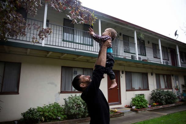 PHOTO: Najib Mohammadi holds his son Yasar Mohammadi in the air to play with leaves outside their apartment in Sacramento, Calif., Nov. 13, 2021. (Brittany Hosea-Small/Reuters)