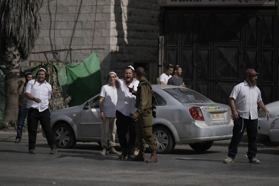 An Israeli soldier talks with Israeli settlers during clashes when the settlers attacked Palestinians in Huwara, near the West Bank town of Nablus, Thursday, Oct. 13, 2022. (AP Photo/Majdi Mohammed)