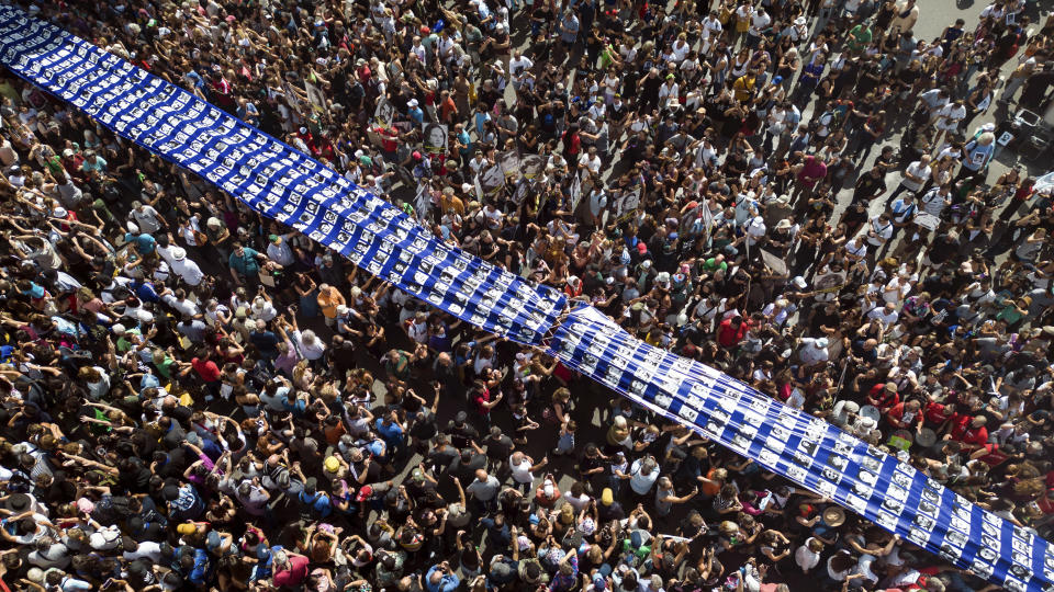 Demonstrators carry a banner with photos of people who disappeared during the 1976-1983 military dictatorship in a march commemorating the 48th anniversary of the coup in Buenos Aires, Argentina, Sunday, March 24, 2024. (AP Photo/Rodrigo Abd)