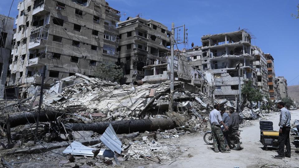 Menschen stehen vor zerstörten Gebäuden in Duma. Hier soll ein mutmaßlicher Chemiewaffenanschlag passiert sein. Foto: Hassan Ammar/AP