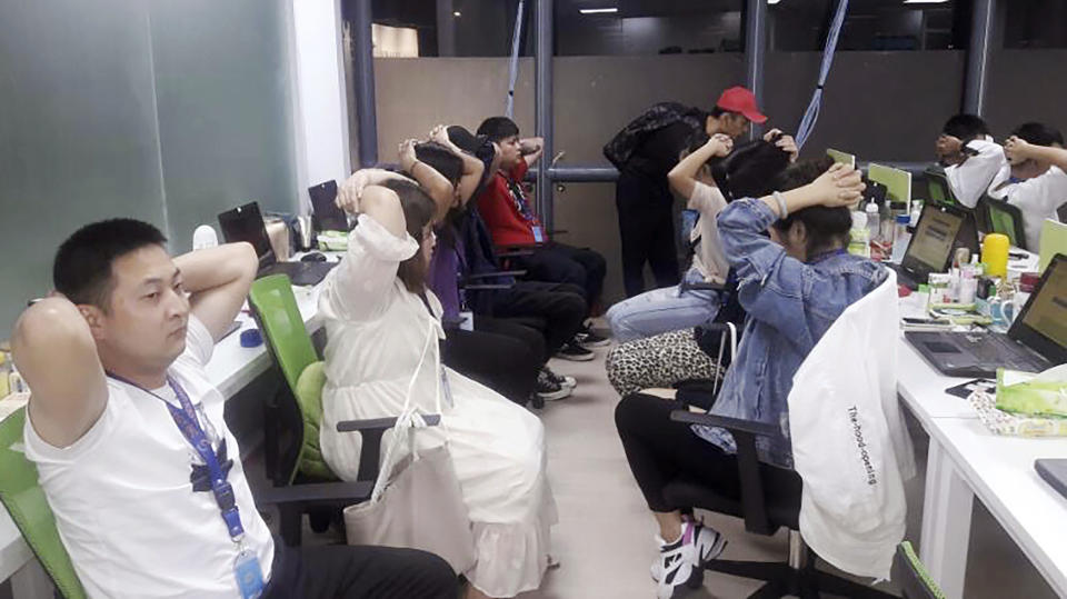 In this Oct. 9, 2019, photo provided by Philippine Bureau of Immigration, foreign nationals, mostly Chinese put their hands on their heads during a raid of their company premises in Manila, Philippines. Philippine police and immigration authorities said they have arrested more than 500 illegally working foreigners, mostly Chinese involved in telecommunications and investment scams, in one of the biggest such mass arrests this year. (Philippine Bureau of Immigration Via AP)