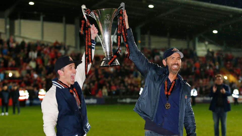 Rob McElhenney and Ryan Reynolds celebrate with the trophy on the pitch.  - Ed Sykes/Action Images/Reuters