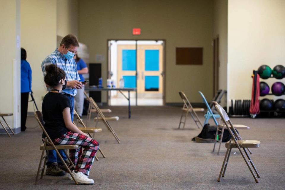 Katie Carter, 12, waits with her father after receiving her first COVID-19 vaccination shot at STEAM Academy in Lexington, Ky., Thursday, May 13, 2021. Close to 60 children 12 and up where scheduled to receive the vaccine at STEAM Academy today.