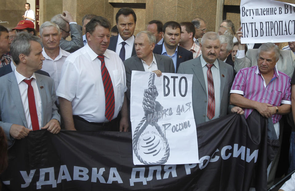 Members of Communist faction of parliament hold banners that read: "WTO is a Noose for Russia", left, and "Joining WTO is the way to the Precipice", at right, as they picket outside the parliament headquarters in Moscow, Russia, Tuesday, July 10, 2012. Russia's parliament is due to ratify an agreement for Russia to join the World Trade Organization in a move that will push Moscow to open up its economy. (AP Photo/Misha Japaridze)