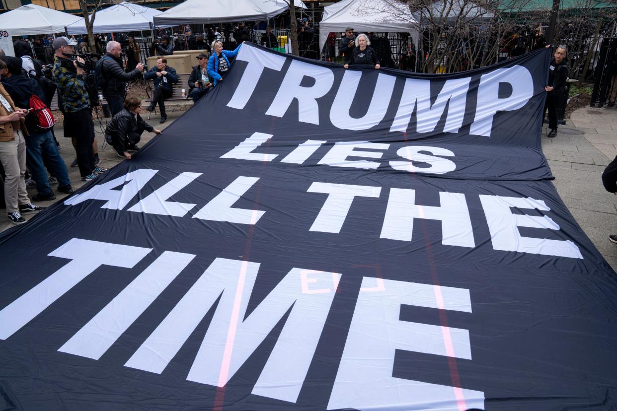 Protesters display a banner criticizing former President Donald Trump outside the Manhattan Criminal Courthouse.