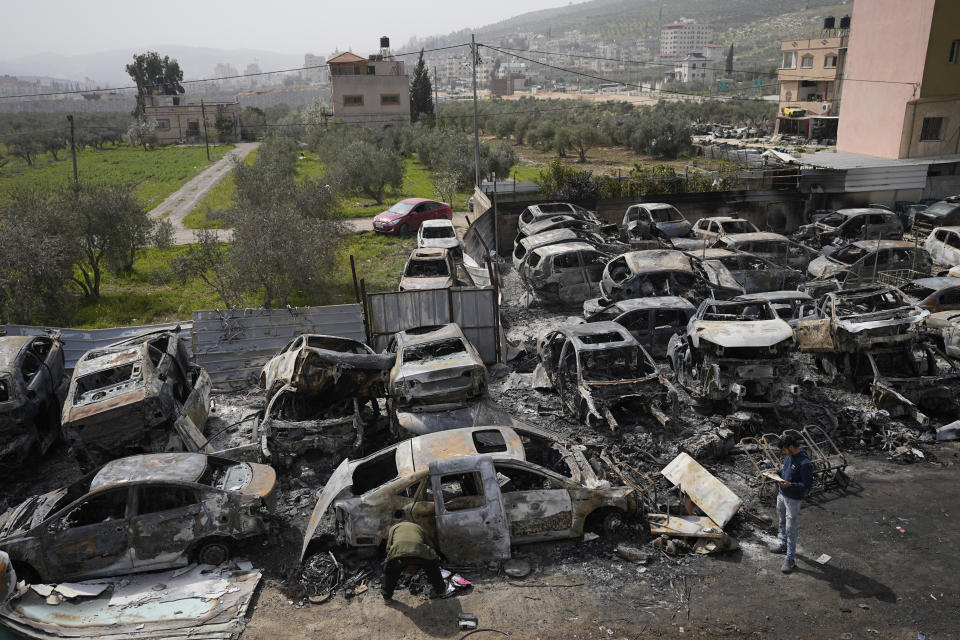 Palestinians inspect scorched cars in a scrapyard, in the town of Hawara, near the West Bank city of Nablus, Monday, Feb. 27, 2023. Scores of Israeli settlers went on a violent rampage in the northern West Bank, setting cars and homes on fire after two settlers were killed by a Palestinian gunman. Palestinian officials say one man was killed and four others were badly wounded. (AP Photo/Ohad Zwigenberg)