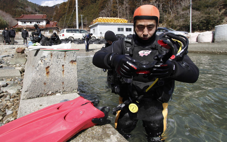 FILE - In this March 9, 2014, file photo, Yasuo Takamatsu prepares to take a diving lesson at Takenoura bay, Miyagi prefecture, northern Japan. Takamatsu, 64, lost his wife, Yuko, when the tsunami hit Onagawa, in Miyagi prefecture. He has been looking for her ever since. He even got his diving license to try to find her remains, and for seven years he has gone on weekly dives. (AP Photo/Koji Ueda, File)