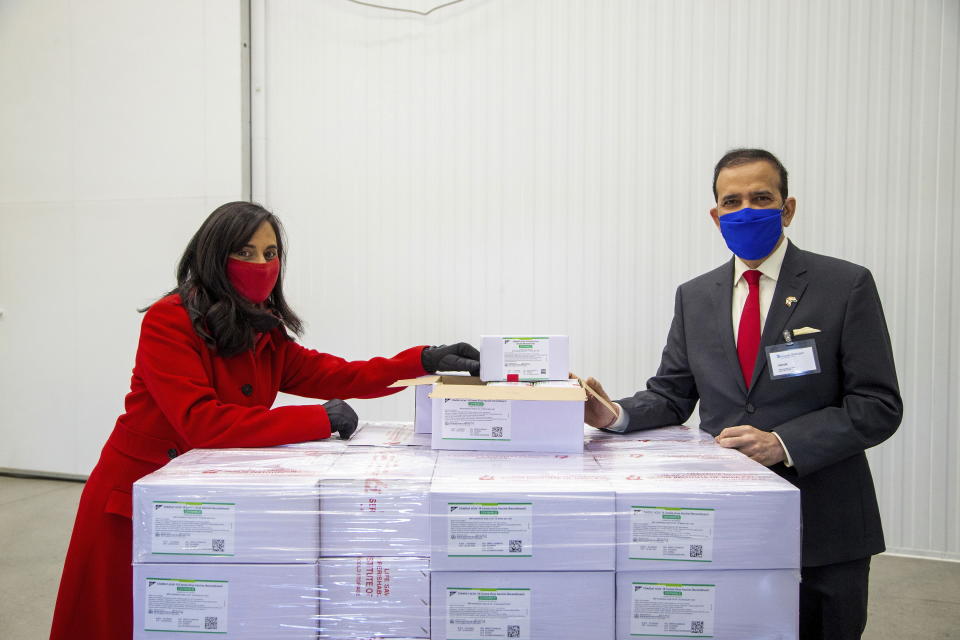 Anita Anand, left, Canada's Minister of Public Services and Procurement and the High Commissioner of India to Canada Ajay Bisaria pose with some of the first 500,000 of the two million AstraZeneca COVID-19 vaccine doses that Canada has secured through a deal with the Serum Institute of India in partnership with Verity Pharma Wednesday, March 3, 2021, at a facility in Milton, Ontario. (Carlos Osorio/Pool Photo via AP)