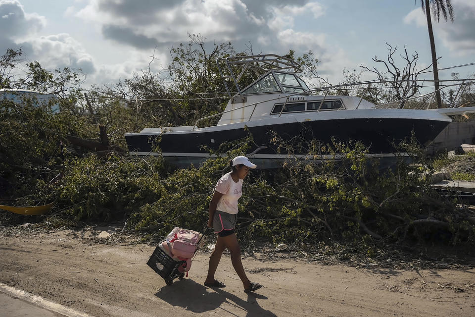 A resident walks past a boat as she arrives to her home to salvage personal items and food in the aftermath of Hurricane Otis in Acapulco, Mexico, Friday, Oct. 27, 2023. Hundreds of thousands of people's lives were torn apart when the fastest intensifying hurricane on record in the Eastern Pacific shredded the coastal city of 1 million. (AP Photo/Felix Marquez)