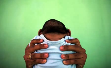 A 4-month-old baby born with microcephaly is held by his mother in front of their house in Olinda, near Recife, Brazil, February 11, 2016. REUTERS/Nacho Doce/Files