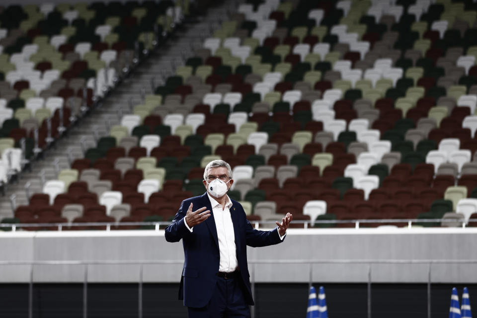 IOC President Thomas Bach wearing a face mask gestures during a visit to the National Stadium, the main venue for the 2020 Olympic and Paralympic Games postponed until July 2021 due to the coronavirus pandemic, in Tokyo Tuesday, Nov. 17, 2020. Bach said during this week's trip to Tokyo that he is “encouraging” all Olympic “participants” and fans to be vaccinated - if one becomes available - if they are going to attend next year's Tokyo Olympics. (Behrouz Mehri/Pool Photo via AP)