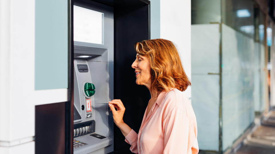 senior woman smiling at atm machine.