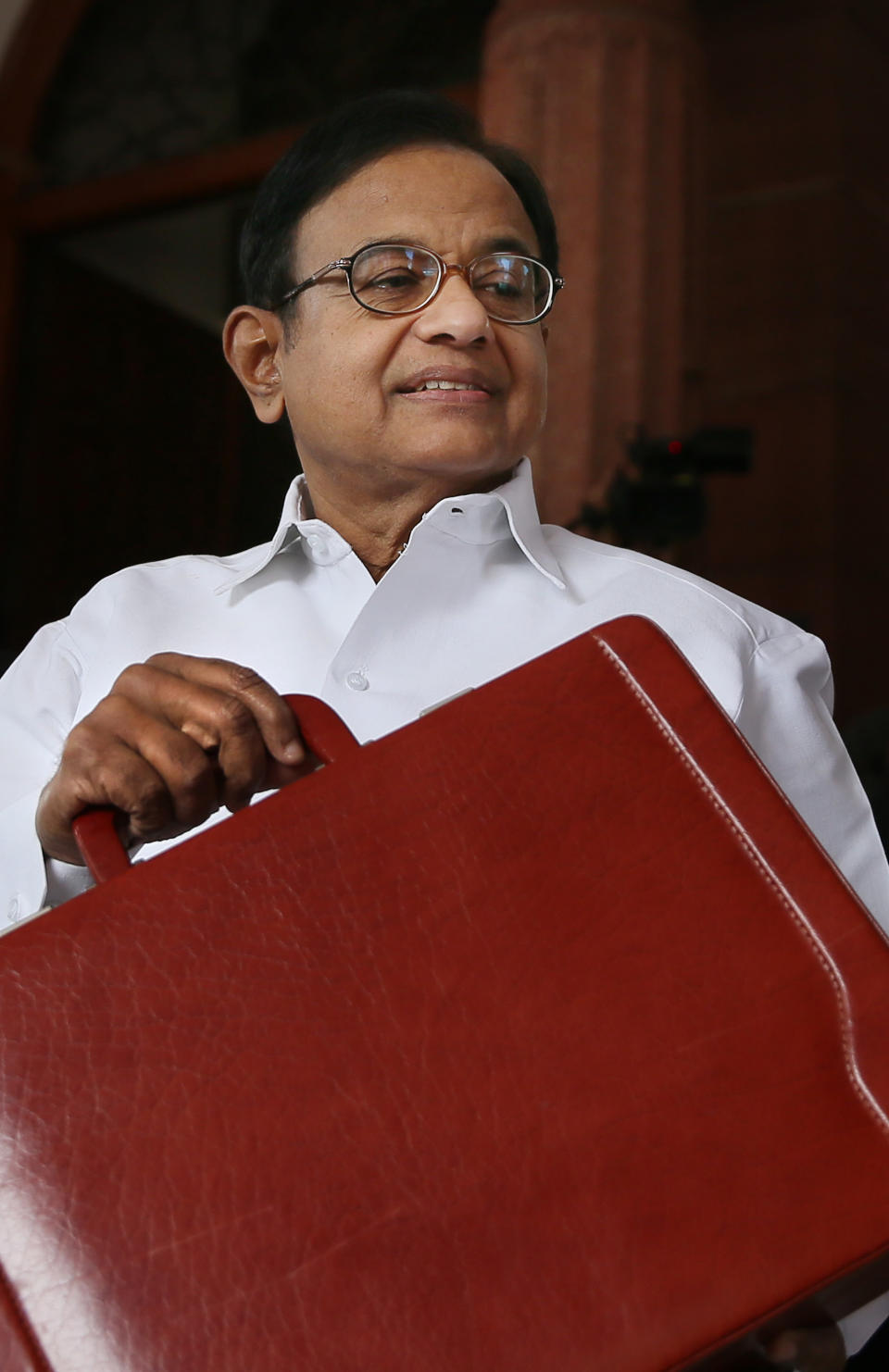 Indian Finance Minister P. Chidambaram shows a briefcase containing interim budget for the fiscal year 2014-15 as he arrives at parliament in New Delhi, India, Monday, Feb. 17, 2014. Chidambaram unveiled a conservative budget for the government’s remaining time in office through May. He said the government has narrowed its fiscal deficit and pledged to keep government spending at the same level. (AP Photo/Manish Swarup)