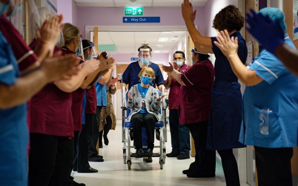 Margaret Keenan, 90, is applauded by staff whilst being pushed down a hallway in a wheelchair after becoming the first person in the UK to receive the Pfizer/BioNtech covid-19 vaccine at University Hospital, Coventry  - Jacob King/PA