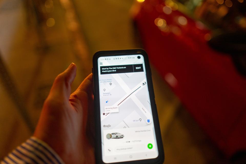 Close-up of hand of a man holding a mobile phone on a city street at night and using the Uber app to hail an Uber ridesharing vehicle, Los Angeles, California, October 27, 2019. Editing note: Photo edited to remove identifying details of driver. (Photo by Smith Collection/Gado/Getty Images)