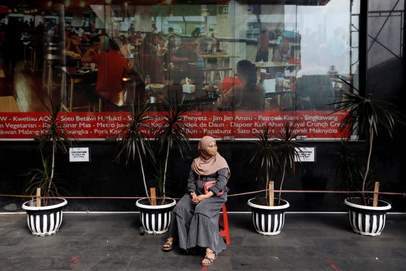 Woman wearing a protective mask following the outbreak of coronavirus disease (COVID-19) sits outside a shopping mall at Tanah Abang textile market in Jakarta