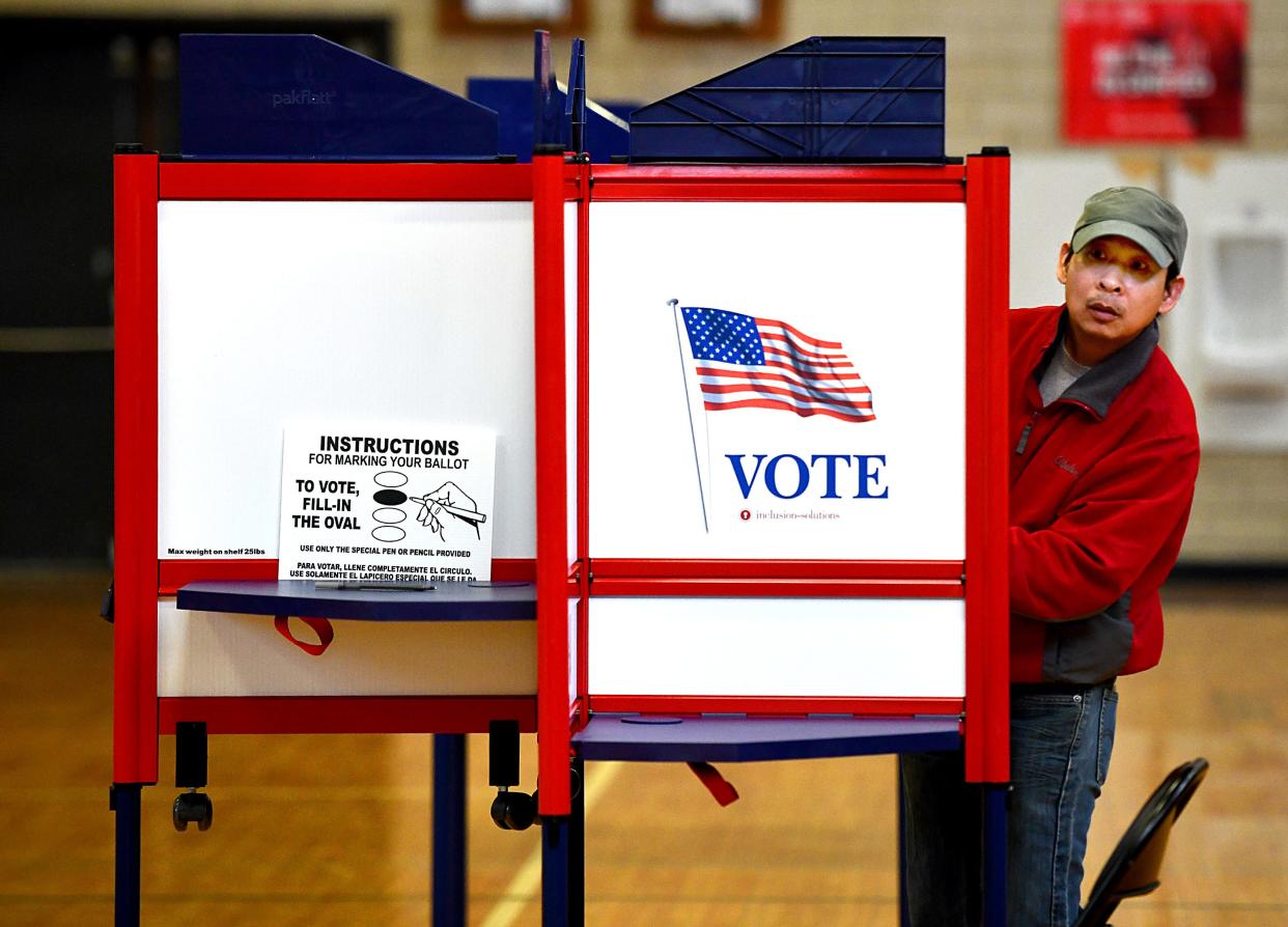 Khai Tran peeks out from his ballot box while voting in Tuesday's primary at Burncoat High School.