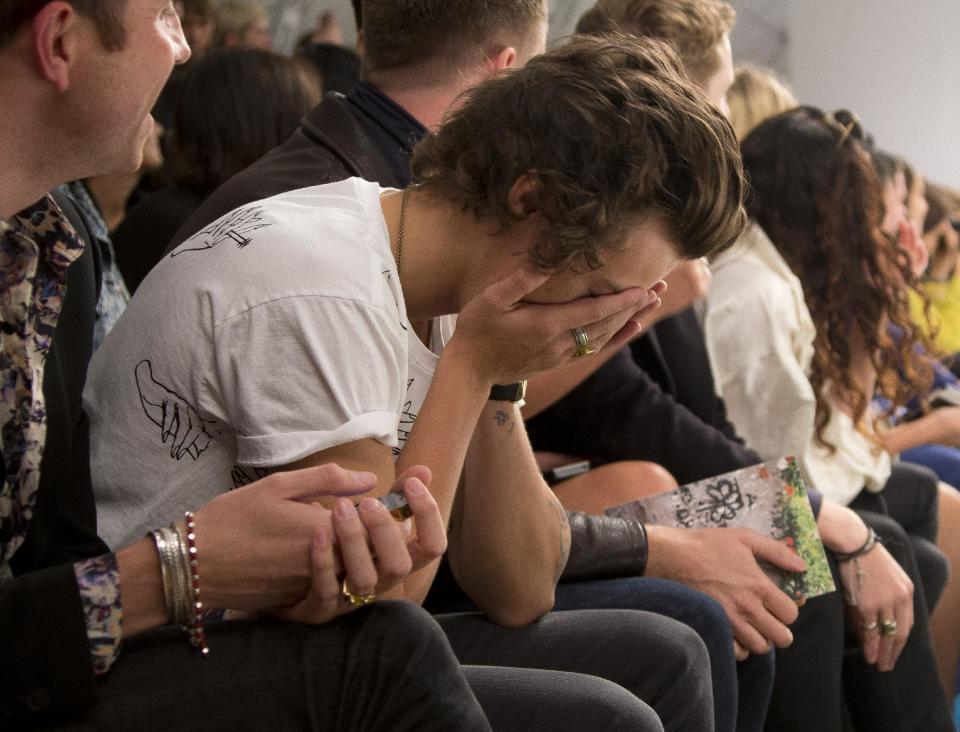 Harry Styles of British band One Direction, covers his face as he watches the Fashion East show by designer Claire Barrow during London Fashion Week Spring/Summer 2014, in Regent's Park, central London, Tuesday, Sept. 17, 2013. (Photo by Joel Ryan/Invision/AP)