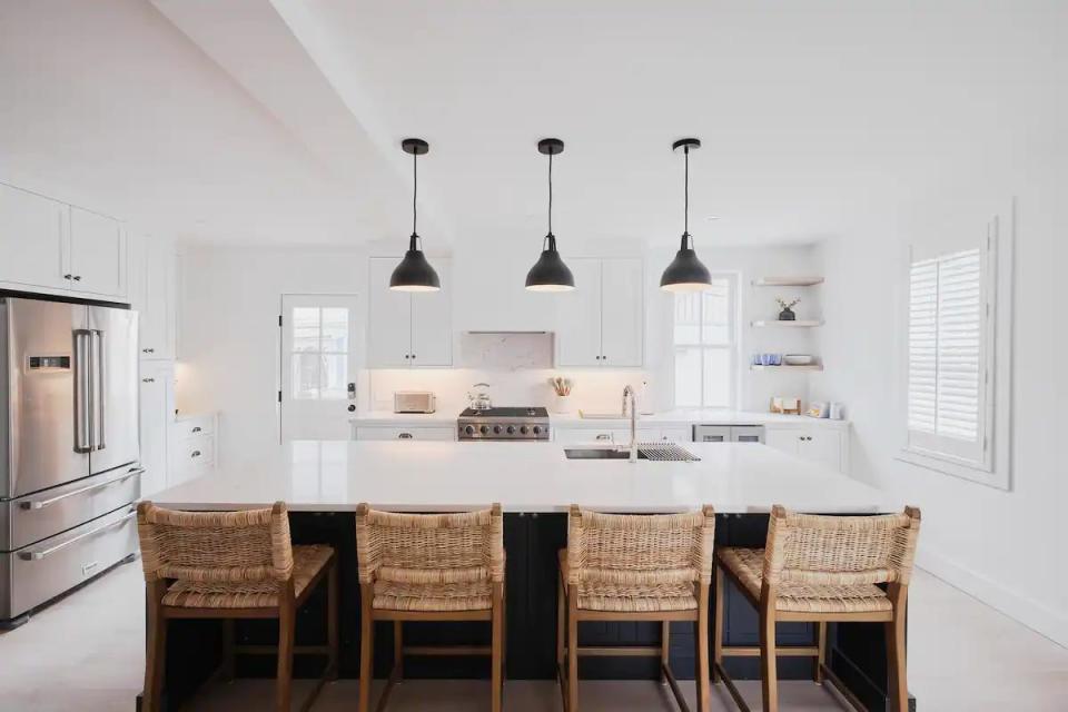 The interiors feature a minimalist, coastal aesthetic with white walls and light-colored furniture.