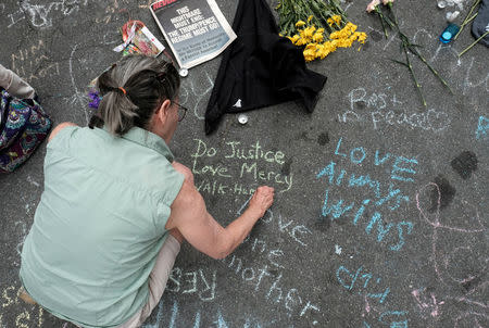 A woman writes a message on the street commemorating the victims at the scene of the car attack on a group of counter-protesters during the "Unite the Right" rally in Charlottesville, Virginia, August 14, 2017. REUTERS/Justin Ide