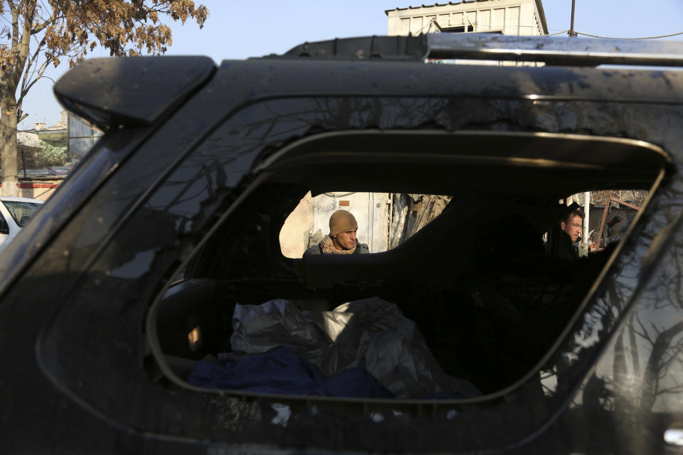Afghan security forces, seen through a broken mirror of a car, investigate the aftermath of Friday's suicide attack and shooting in Kabul, Afghanistan, Saturday, Jan. 18, 2014. A suicide bomber blew himself up outside a Kabul restaurant filled with foreigners and affluent Afghans, while two gunmen snuck in through the back door and opened fire Friday in a brazen dinnertime attack that killed 16 people, officials said. (AP Photo/Rahmat Gul)
