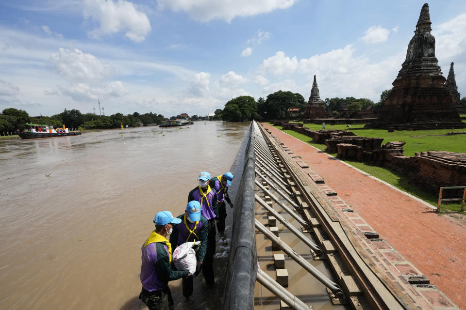 Soldiers stack sandbags to protect Wat Chaiwatthanaram from possible rising flood waters in Ayutthaya province, north of Bangkok, Thailand, Monday, Sept. 27, 2021. Seasonal monsoon rains may worsen flooding that has already badly affected about a third of Thailand, officials said Monday as flood gates and pumping stations were being used to mitigate the potential damage. (AP Photo/Sakchai Lalit)