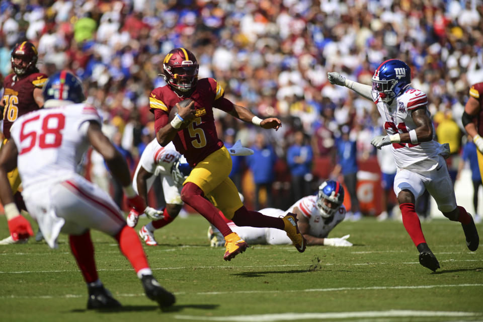 Washington Commanders quarterback Jayden Daniels (5) runs as New York Giants safety Tyler Nubin and Bobby Okereke (58) pursue during the first half of an NFL football game in Landover, Md., Sunday, Sept. 15, 2024. (AP Photo/Steve Ruark)