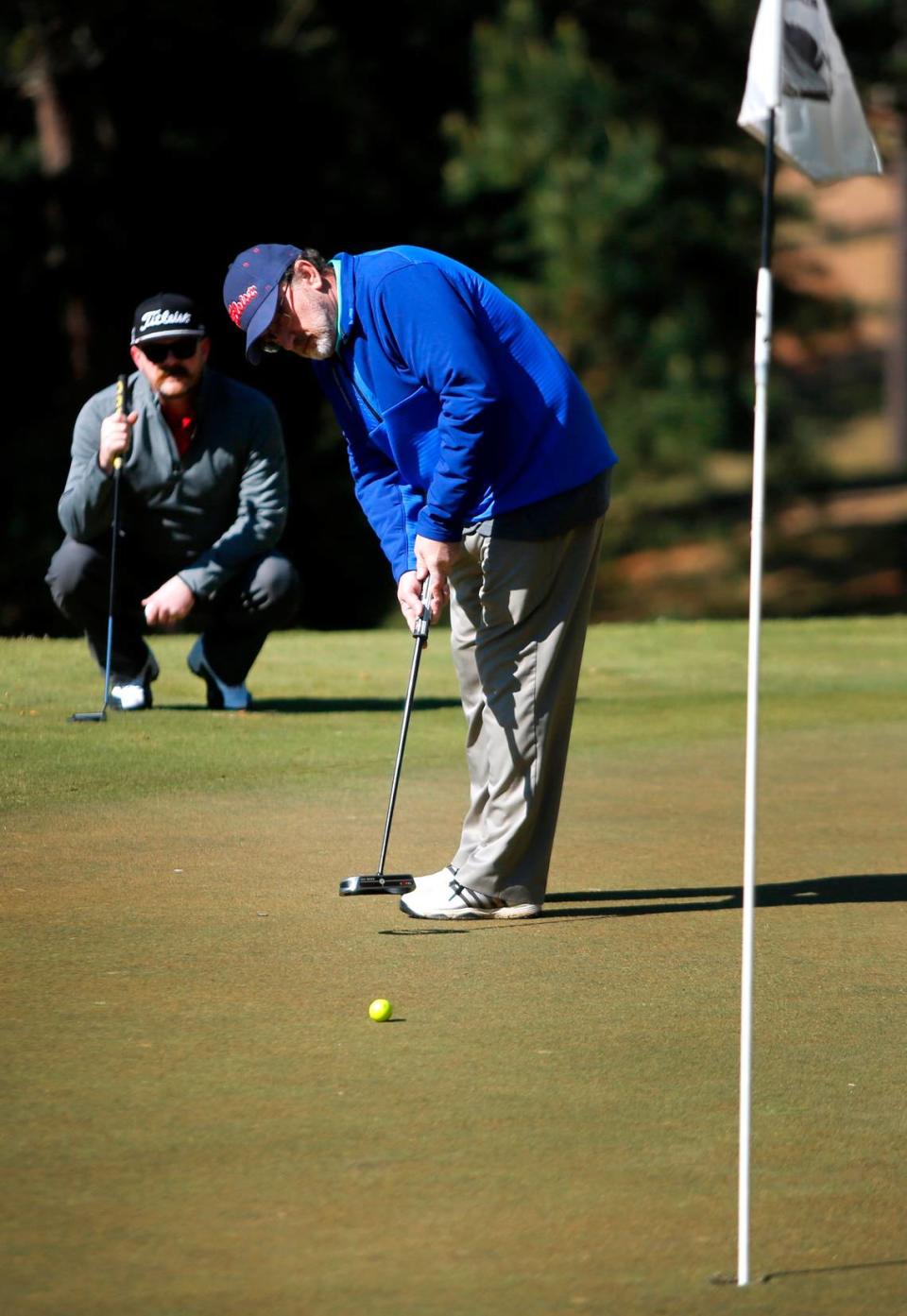 Greg Hooper, front, a golfer with the United States Blind Golf Association, putts as his son and coach Alan Hooper watches Monday morning during a practice round for a tournament this week at Green Island Country Club in Columbus, Georgia. 03/20/2023