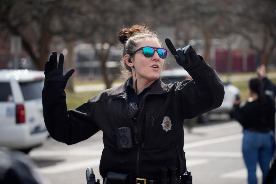 A Denver Police officer directs parents to meet their children following a shooting at East High School, Wednesday, March 22, 2023, in Denver (AP)