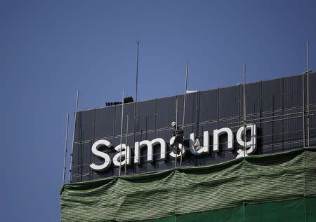 A worker works on a Samsung outdoor advertisement installed atop an office building in central Seoul March 23, 2015. REUTERS/Kim Hong-Ji