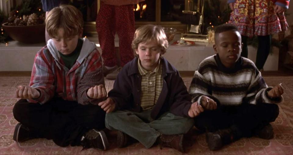 Three kids sit cross-legged on the floor, meditating at a party