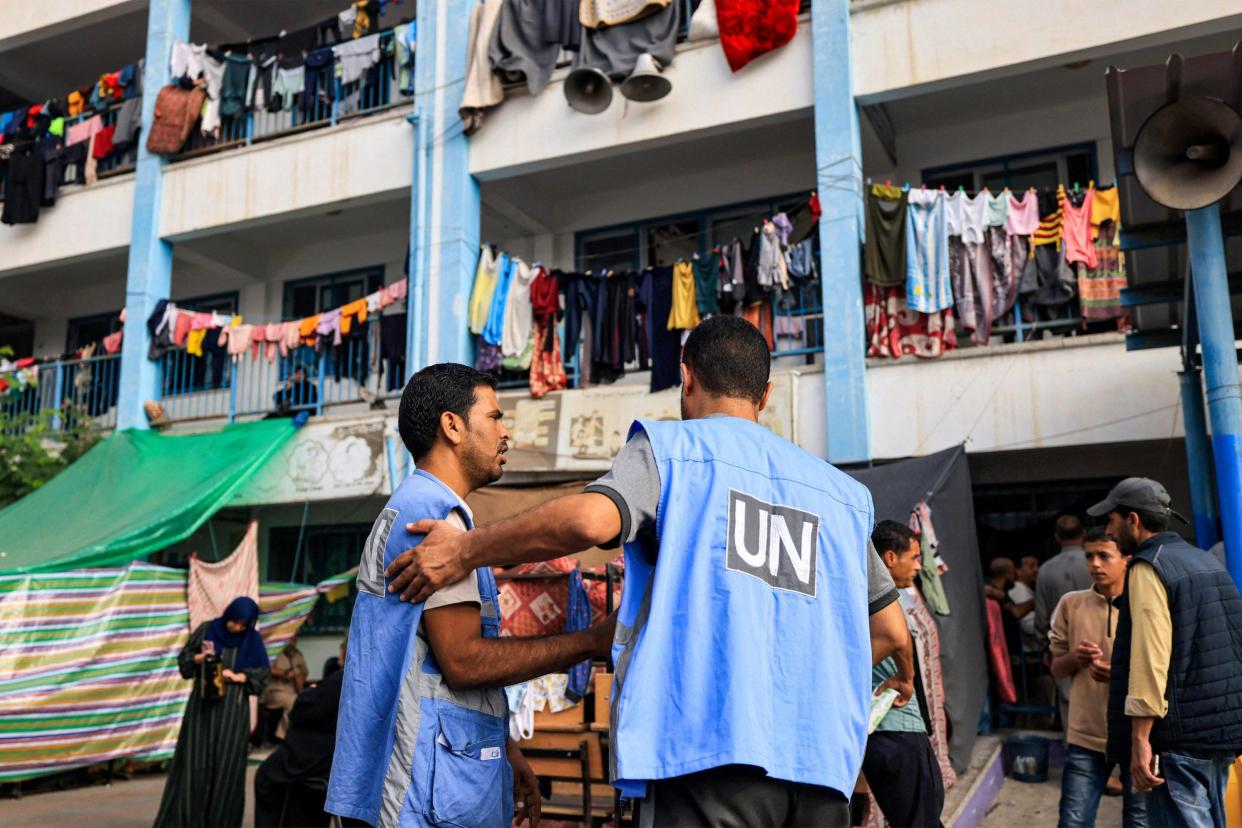 Workers of the United Nations Relief and Works Agency for Palestine Refugees (UNRWA) agency talk together in the playground of an UNRWA-run school that has been converted into a shelter for displaced Palestinians in Khan Yunis in the southern Gaza Strip