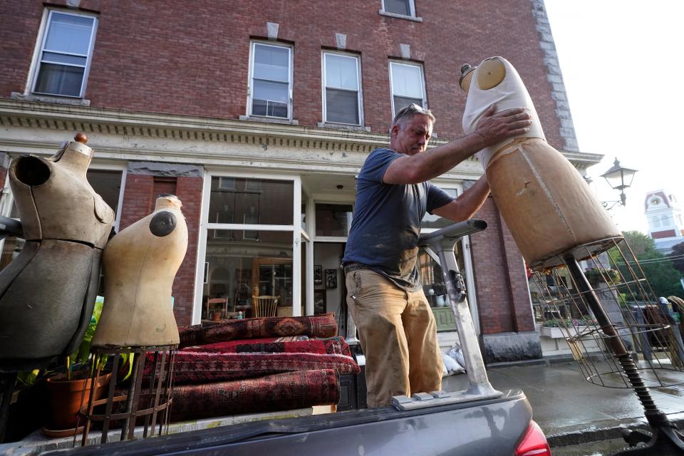 Simon Jennings, of Montpelier, Vt., removes mid-20th century mannequins from the flood-damaged antique, art, and furnishing store (AP)