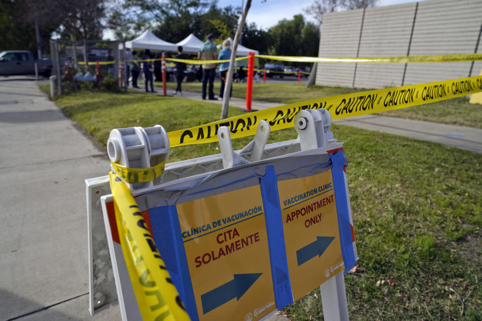 A sign points to a line at a COVID-19 vaccination site for health care workers at Ritchie Valens Recreation Center Wednesday, Jan. 13, 2021, in Pacoima, Calif. (AP Photo/Marcio Jose Sanchez)