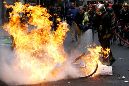 A fireman extinguishes a burning bicycle during clashes with yellow vests protesters as part of a national day of protest by the "yellow vests" movement in Paris, France, December 8, 2018. REUTERS/Stephane Mahe