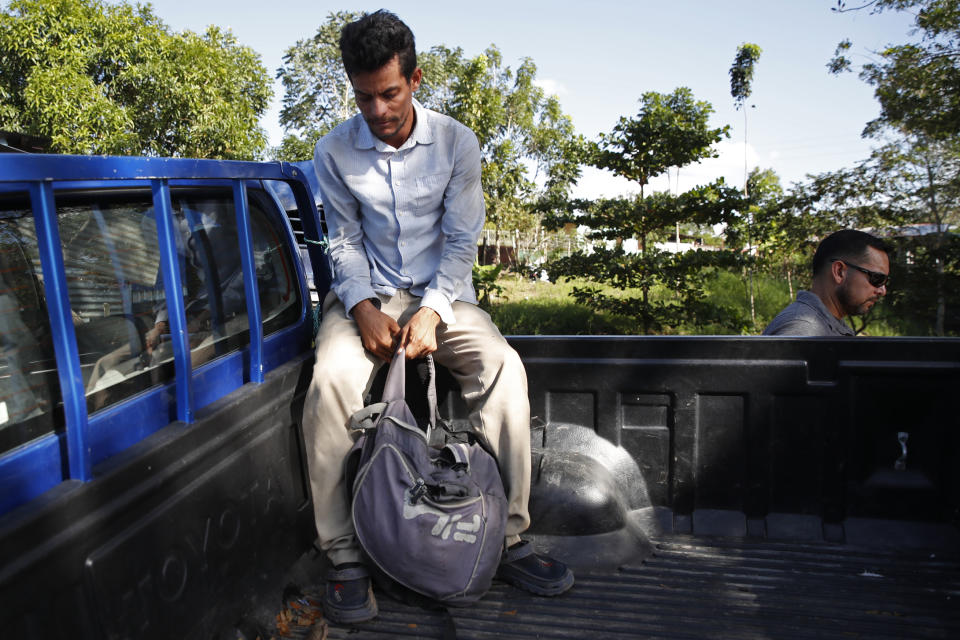 An agent from U.S. Immigration and Customs Enforcement (ICE), right, walks past a Honduran migrant sitting in the bed of a police truck at a checkpoint in Morales, Guatemala, Wednesday, Jan. 15, 2020, before the migrant is deported. Since about May 2019, Homeland Security has deployed dozens of agents and investigators to Guatemala to work as “advisers” to the national police there and migration officials. (AP Photo/Moises Castillo)